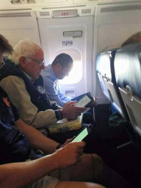 A picture of Bernie Sanders sitting in coach.
