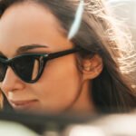 A woman with polarized sunglasses on in the rear view mirror.