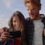 A picture of a couple looking at a cellphone