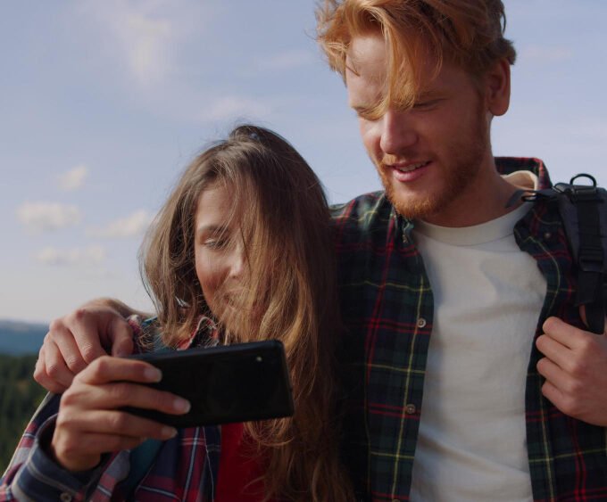 A picture of a couple looking at a cellphone